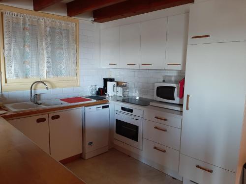 une cuisine avec des armoires blanches, un évier et un micro-ondes dans l'établissement Le Petit Michelet, à Granville