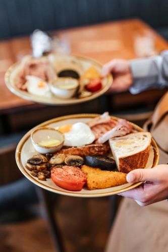a person holding a plate of breakfast foods at Oyster House in The Mumbles
