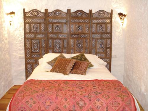 1 dormitorio con 1 cama grande y cabecero de madera en Cueva de La Alegría, en Huéscar