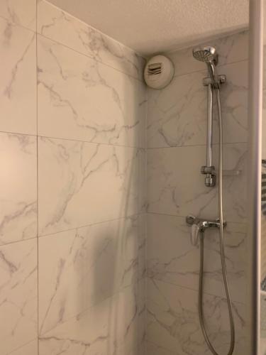 a bathroom with a shower with white marble walls at Kyriad SEDAN in Sedan
