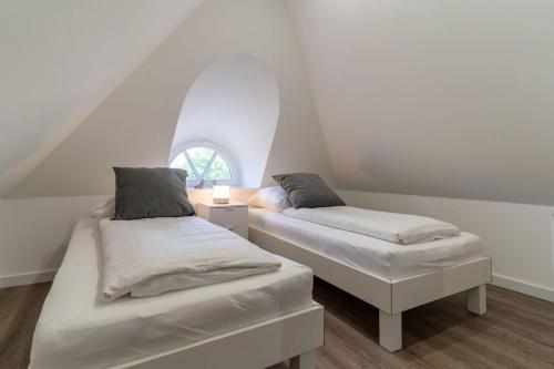 two beds in a room with a window at Reetdachhaus Taschenkrebs Reetdachhaus Taschenkrebs in Sankt Peter-Ording