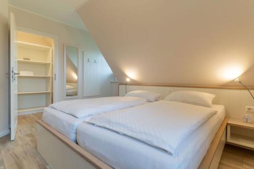 a white bedroom with two beds and a closet at Reetdachhaus Boy's Huus Reetdachhaus Boy's Huus 5a in Sankt Peter-Ording