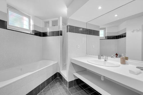 La salle de bains blanche est pourvue d'un lavabo, d'une baignoire et d'un miroir. dans l'établissement LE MERCIER - Grand T4 de 100m2 en plein coeur de Toulouse, à Toulouse