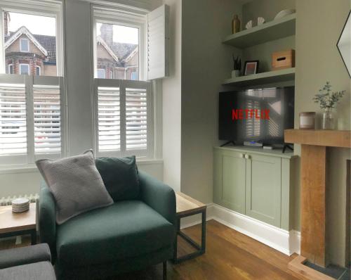 a living room with a green chair and a tv at Emerson House, dog friendly with log burner close to waters edge and harbour in Poole