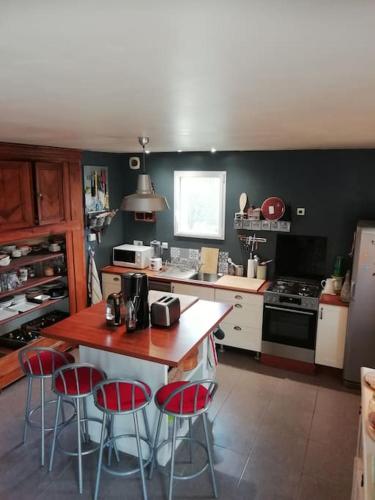 - une cuisine avec une table et quatre tabourets dans l'établissement Maison familiale sur la CÔTE D’ÉMERAUDE, à Lancieux