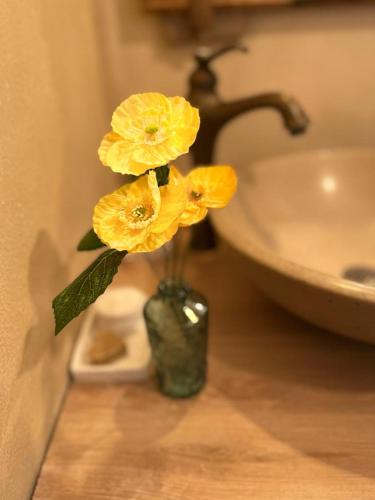 a vase with yellow flowers in it next to a sink at TENDANCE CAMPAGNE Chambre d'hôtes in Marillac