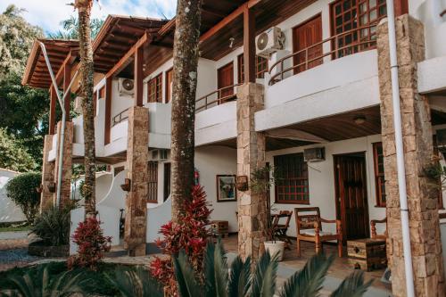 a house with a balcony and palm trees at HOTELARE Hotel Brunello in Paraty