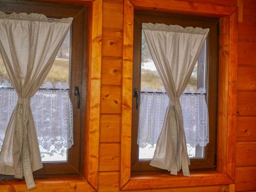two windows in a wooden room with curtains at Penzión Hron - Beňuš in Beňuš