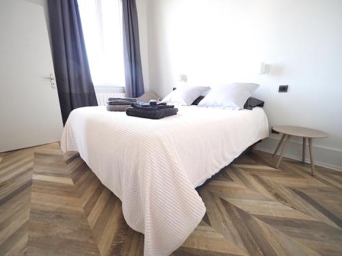 a bedroom with a large white bed with a wooden floor at Superbe appartement indépendant en centre ville in Vichy
