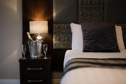a bedroom with a bed with a lamp and wine glasses at Buchanan Arms Hotel & Leisure, Sure Hotel Collection in Drymen