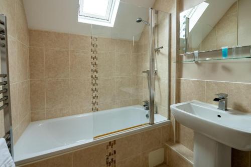 a bathroom with a bath tub and a sink at Buchanan Arms Hotel & Leisure, Sure Hotel Collection in Drymen