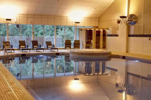 a swimming pool with chairs and a tub in a building at Buchanan Arms Hotel & Leisure, Sure Hotel Collection in Drymen