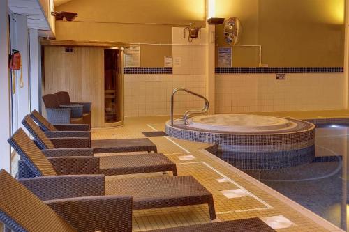 a room with chairs and a tub in a bathroom at Buchanan Arms Hotel & Leisure, Sure Hotel Collection in Drymen