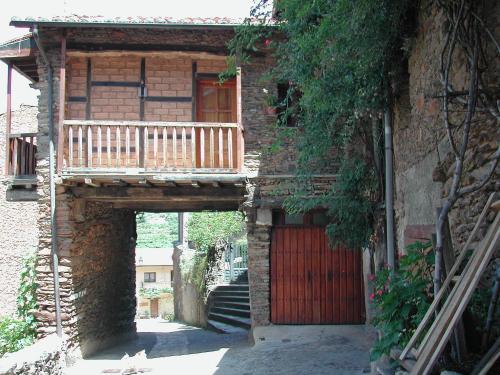 a building with a wooden balcony and a door at Casa Rural Valle del Arrago in Robledillo de Gata