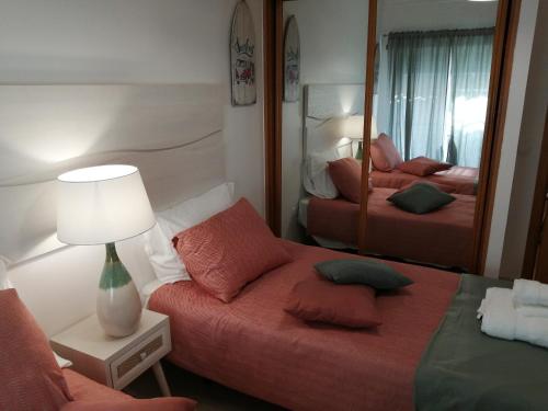 a small bedroom with a bed and a mirror at Apartamento de 2 Quartos no Centro de Monte Gordo in Monte Gordo