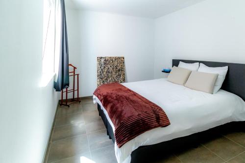 a bedroom with a white bed with a red blanket at Laluna holiday apartment in Ostend