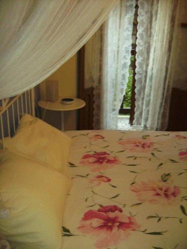 a bed with pink flowers on it with a window at Casa Rural Valle del Arrago in Robledillo de Gata