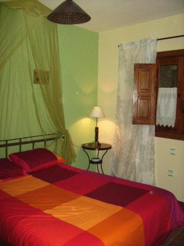 a bedroom with a colorful bed and a window at Casa Rural Valle del Arrago in Robledillo de Gata