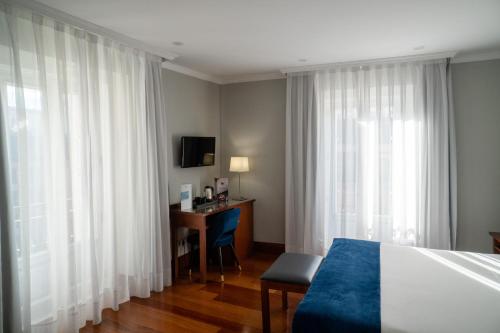 a hotel room with a bed and a desk and curtains at Hotel Infantas by MIJ in Madrid