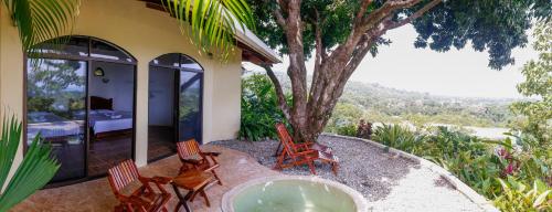 a house with chairs and a tub in front of a tree at LagunaVista Villas in Carate
