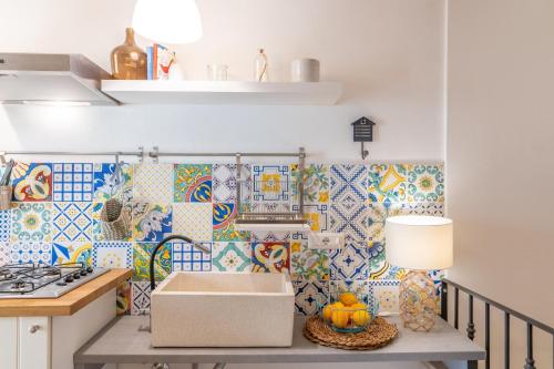 una cucina con piastrelle colorate sul muro e un tavolo con una scatola di Casa Talete Cozy Apartment in Ortigia - FIRST FLOOR a Siracusa