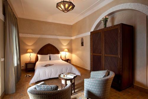 ein Hotelzimmer mit einem Bett und zwei Stühlen in der Unterkunft Riad Les Bougainvilliers in Marrakesch