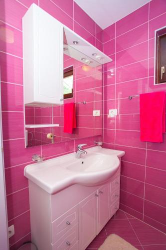a pink bathroom with a sink and a mirror at Apartmani Centar Makarska in Makarska
