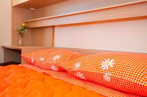 two orange pillows sitting on top of a bed at Apartmani Centar Makarska in Makarska