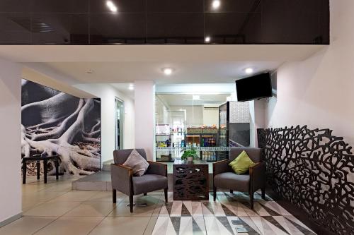 a lobby with two chairs and a tv on a wall at Gamma Villahermosa Centro in Villahermosa