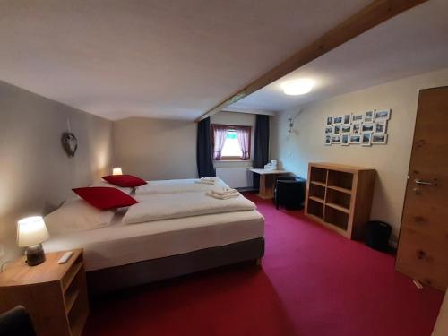 a bedroom with a large white bed with red pillows at Pension Zeegershof in Heiterwang