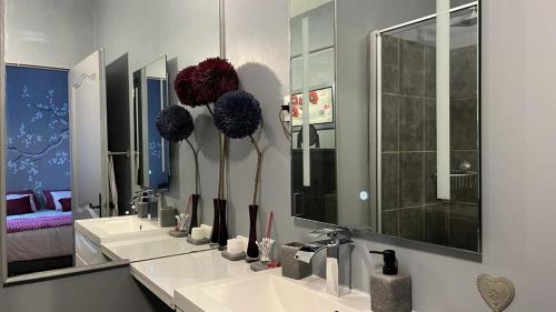 a bathroom with three sinks with vases on the mirror at TENDANCE CAMPAGNE Chambre d'hôtes in Marillac