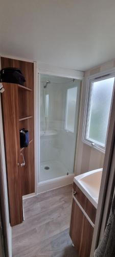 La salle de bains est pourvue d'une douche et d'un lavabo blanc. dans l'établissement Mobil home Familial, à La Roque-dʼAnthéron