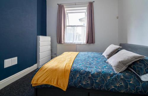 a bedroom with a bed with a yellow blanket and a window at Stunning Victorian House in Hull