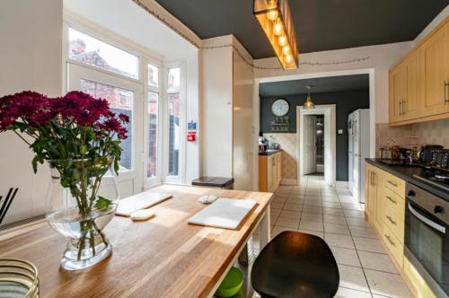 a kitchen with a vase of flowers on a wooden table at Stunning Victorian House in Hull