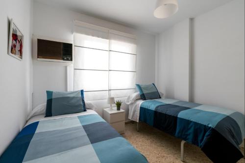 Un dormitorio con dos camas y una ventana en BeHouse Mairena, en Mairena del Aljarafe