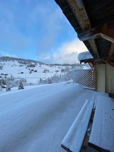 a porch covered in snow with a bench on it at La Ferme des Georgières "Séjour en tout compris" in Notre-Dame-de-Bellecombe