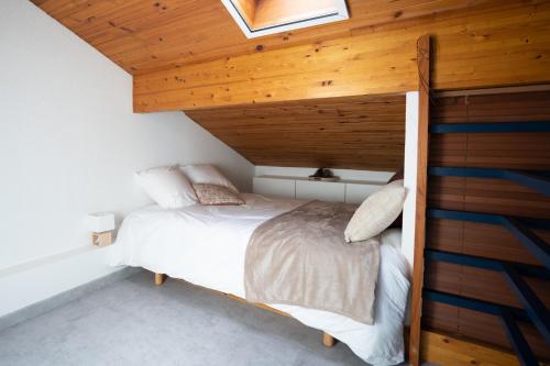 Ce lit se trouve dans un dortoir doté d'un plafond en bois. dans l'établissement Chaleureux appartement à 500m de l’océan et 150m du Golf Moliets-Plage, à Moliets-et-Maa