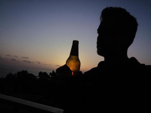 un uomo che tiene in mano una bottiglia di vino al tramonto di ZAMBRONE VILLAGE Loris a Zambrone