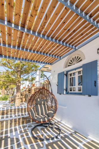 a patio with a wicker chair under a wooden pergola at Θἔρως (Theros) house 3- Agios Fokas in Agios Sostis