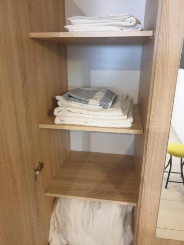 a closet with wooden shelves and folded towels at comfy center rodos - blue in Asgourou