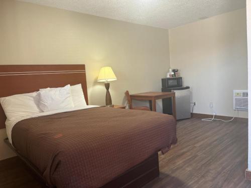 a bedroom with a bed and a table with a lamp at Valley Motel in Alamosa