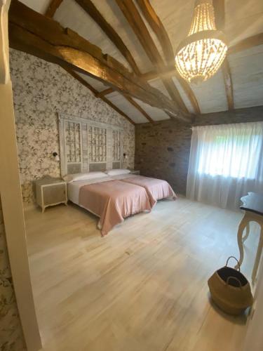 a bedroom with a large bed and a chandelier at Casa Meiga in Arzúa