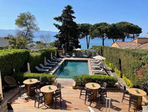 a resort with a pool and tables and chairs at Hôtel La Pinède in Ajaccio