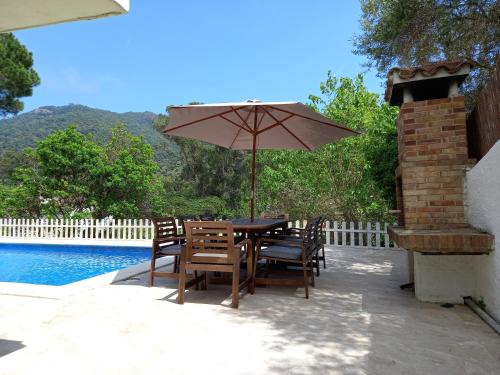 a table and chairs with an umbrella next to a pool at Villa Rosamar - Canyet de Mar in Cañet de Mar