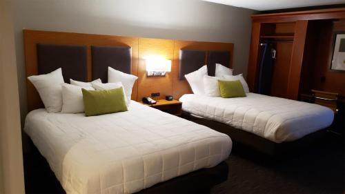 two beds in a hotel room with white sheets and green pillows at MainStay Suites Springfield IL in Springfield