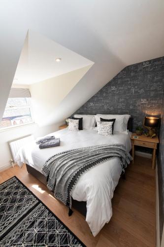 a bedroom with a large white bed with a brick wall at 3 Bedroom House - a very British place to stay - near city centre ! in Oxford