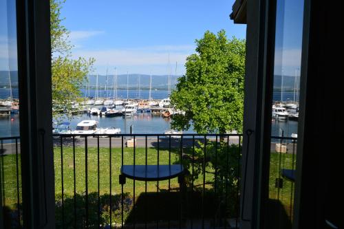 a balcony with a view of a marina with boats at Hôtel Le Jules Verne in Yvoire