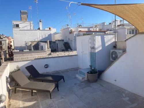 a patio with two chairs and a table on a roof at Tresor 65 in Polignano a Mare