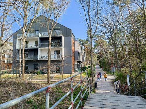 people walking down a stairs in front of a building at SEA & YOU Apartament z widokiem na morze - Dwie Sosny in Ustronie Morskie