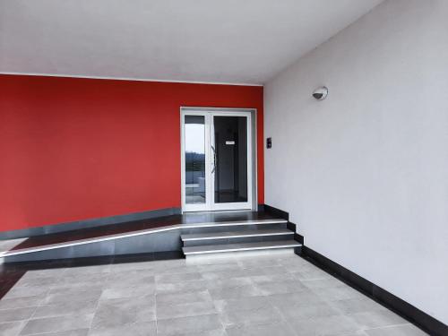 an empty room with a red wall and stairs at NSM Blumarine Attico con servizio spiaggia in Campomarino